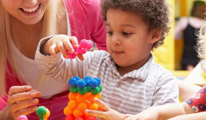 Little boy playing with learning toys with a teacher's aid